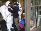 A student adjusts the fishbowl helmet of a student's astronaut suit.